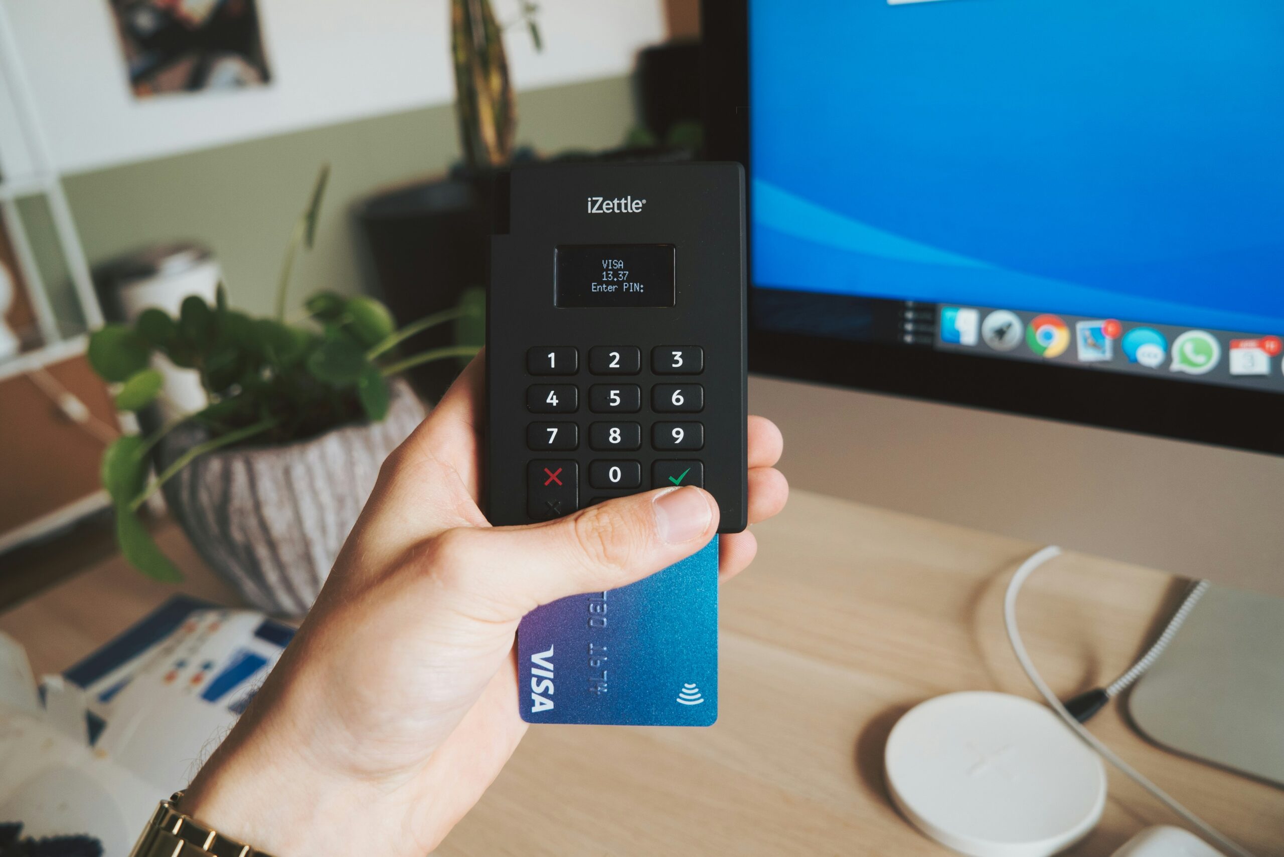 Hand holding an eftpos machine with a credit card in it.